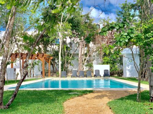 a swimming pool in a resort with chairs and trees at Beautiful 3 BR/3.5 bath Home@Selvanova in Playa del Carmen