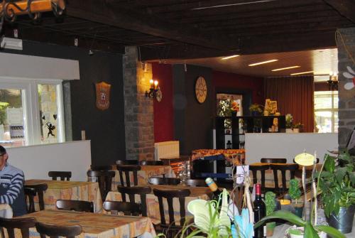 a restaurant with tables and chairs and a clock on the wall at Hotel Beco in Banneux