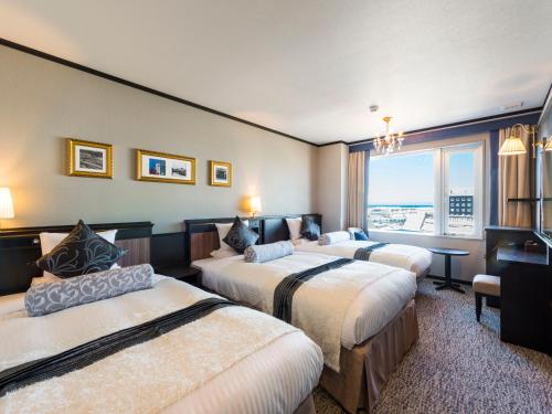 a hotel room with three beds and a window at Hotel Sonia Otaru in Otaru