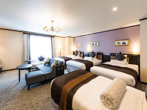 a hotel room with four beds and a chandelier at Hotel Sonia Otaru in Otaru