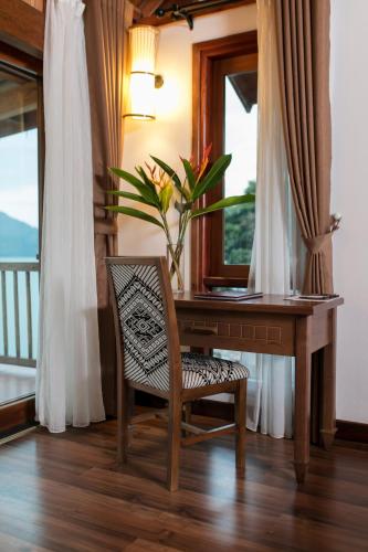 a desk with a chair and a vase of flowers at Mai Chau Hideaway Lake Resort in Mai Chau