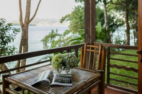 a table with a vase of flowers and books on a porch at Mai Chau Hideaway Lake Resort in Mai Chau