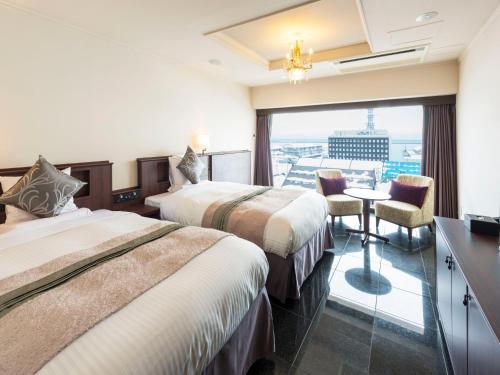 a hotel room with two beds and a table with chairs at Hotel Sonia Otaru in Otaru