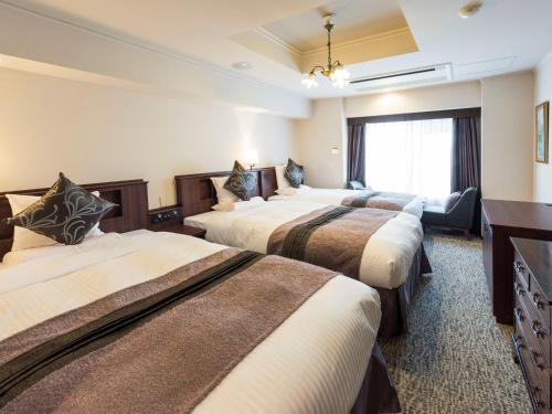 a hotel room with three beds and a window at Hotel Sonia Otaru in Otaru