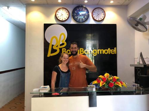 a man and a woman standing in a room with clocks at BangBang Motel in Can Tho