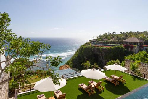 a view of the ocean from a resort with chairs and umbrellas at Villa Maiara in Uluwatu