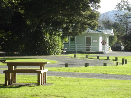 a picnic table in a park with a building in the background at Greytown Campground in Greytown