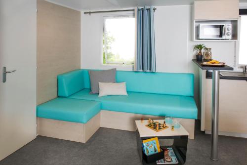 ein Wohnzimmer mit einem blauen Sofa und einem Tisch in der Unterkunft Camping du canal in Kembs