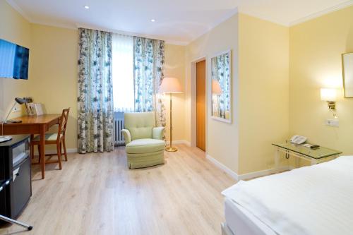 a hotel room with a bed and a desk and a chair at Romantik Waldhotel Mangold in Bergisch Gladbach