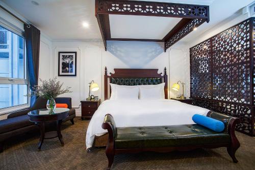 ハノイにあるNew Era Hotel & Villaのベッドルーム(大きな白いベッド1台、緑のベンチ付)
