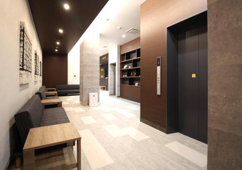 a lobby with a waiting room with a couch and tables at Arigato Stay Kanazawa Ekimae in Kanazawa