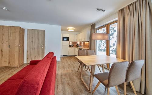a living room with a red couch and a table at AlpenParks Hotel & Apartment Sonnleiten in Saalbach Hinterglemm