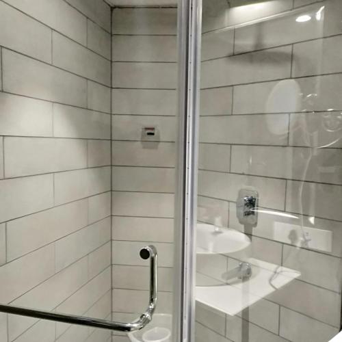 a bathroom with a shower and a sink at De Mandarin in Bengaluru