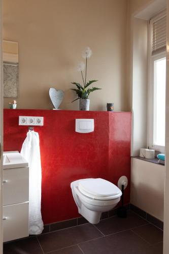 a bathroom with a white toilet and a red wall at Ferienwohnung Bodil in Handewitt