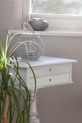 a white table with a plant sitting next to a window at Ferienwohnung Bodil in Handewitt