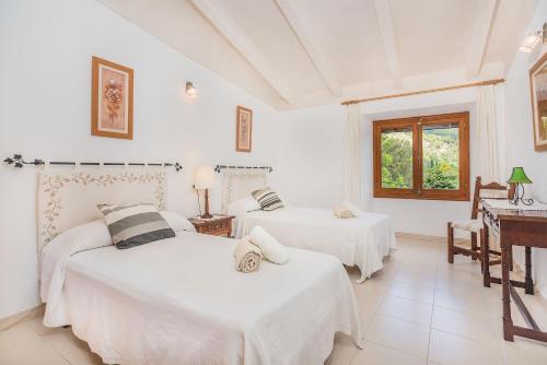 two beds in a white room with a piano at Villa Can Pau By SunVillas Mallorca in Pollença