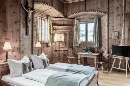 a bedroom with a bed and a desk and a television at Hotel Jagdschloss Resort in Kühtai