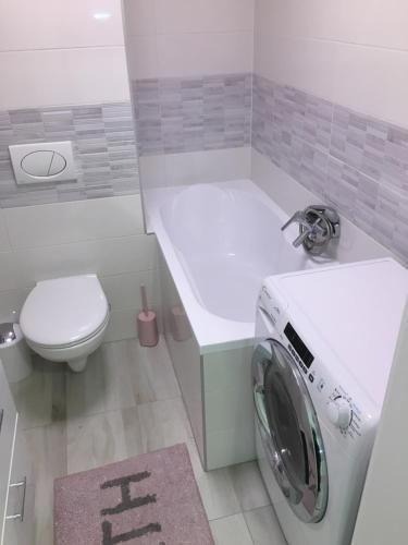 a washing machine in a bathroom with a toilet at Rose Central Apartment in Debrecen