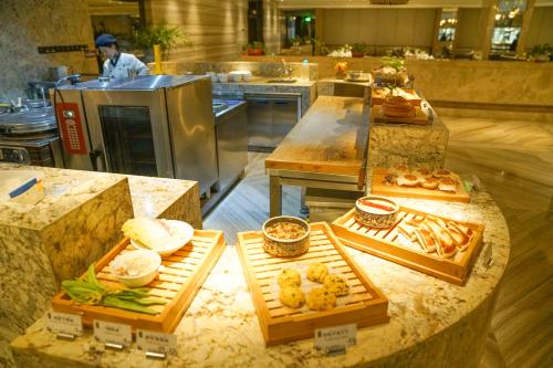 a kitchen with several different types of food on display at Yantai Meiya International ApartHotel (Previous Ramada Plaza) in Yantai