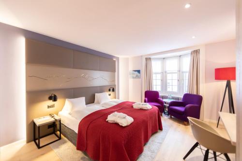 Habitación de hotel con 1 cama y 2 sillas moradas en Hotel Rosatsch en Pontresina