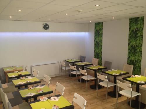 une salle à manger avec des tables, des chaises et une horloge murale dans l'établissement Hôtel Beaulieu, à Clermont-Ferrand