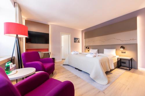 a hotel room with a bed and purple chairs at Hotel Rosatsch in Pontresina