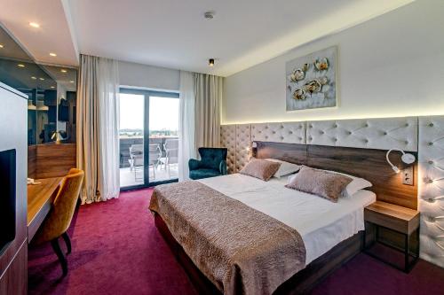a bedroom with a bed and a desk and a balcony at Hotel Scala d'Oro in Vodice