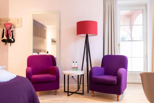 two purple chairs and a lamp in a bedroom at Hotel Rosatsch in Pontresina