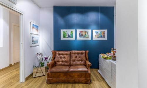 un fauteuil en cuir brun dans une chambre aux murs bleus dans l'établissement OTTO Rooms & Photogallery, à Rome