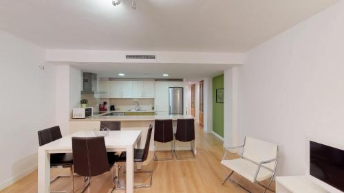 a kitchen and dining room with a white table and chairs at Edificio Palomar - PalomarGroup in Valencia