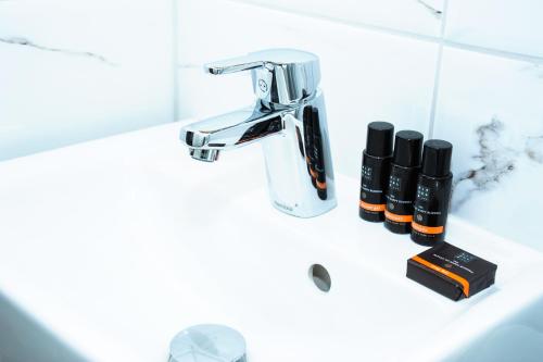 a bathroom sink with a faucet and two bottles of lipstick at Hotel Gamla Stan, BW Signature Collection in Stockholm