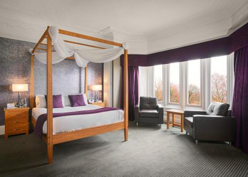 a bedroom with a canopy bed and a chair at Burnley West Higher Trapp Hotel in Padiham