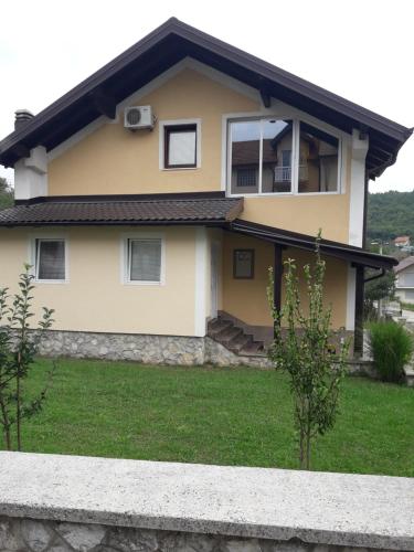 una casa amarilla con una valla delante de ella en Sweet Holiday Home, en Hadžići