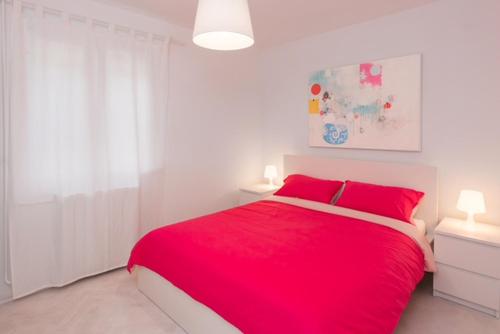 Una cama roja con almohadas rojas en un dormitorio blanco en ArtApArt D, en Rabac