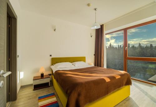 a bedroom with a bed and a large window at Timber view apartment Silver Mountain Poiana Brasov in Poiana Brasov