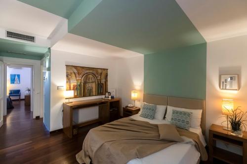 a bedroom with a bed and a painting on the wall at Hotel Pocho in San Vito lo Capo