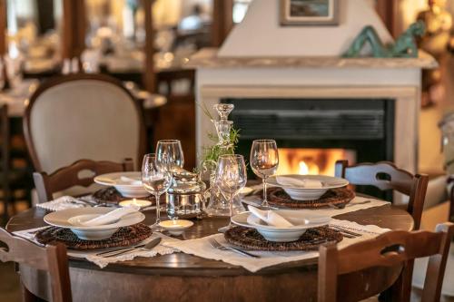 a table with glasses and plates on it with a fireplace at Hotel Pocho in San Vito lo Capo