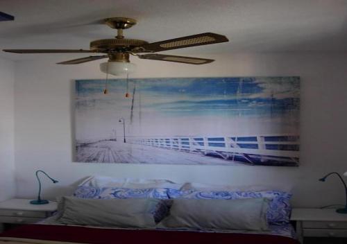 un ventilador de techo en la sala de estar con una pintura en la pared en Calablu, en Alicante