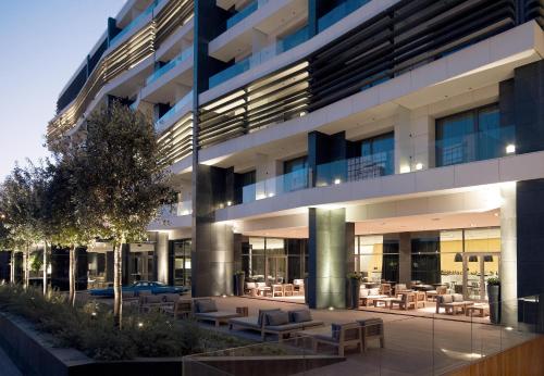 un edificio con tavoli e sedie in un cortile di The Met Hotel Thessaloniki, a Member of Design Hotels a Salonicco