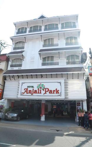 a large white building with a sign for a park at Hotel Anjali Park in Kottayam