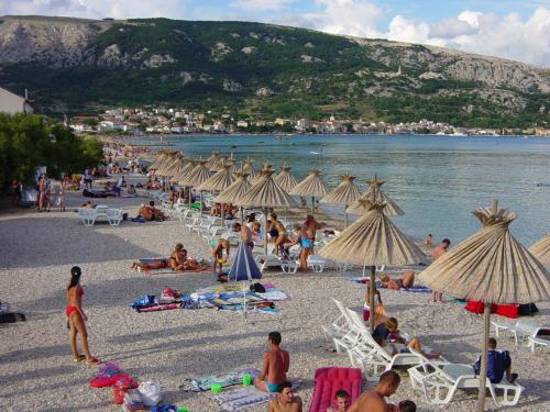 a group of people on a beach with umbrellas at Apartments Mrkus in Baška