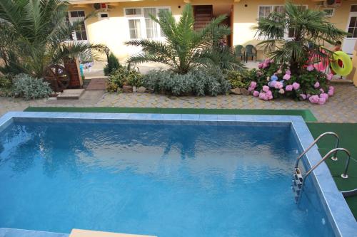 una gran piscina azul en un patio con plantas en Guest House Planet MOV, en Adler