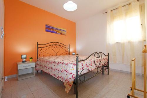 una camera con un letto con una parete arancione di Casa fronte spiaggia a Marina di Pescoluse