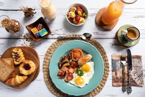 a table topped with a plate of eggs and breakfast foods at Kambaku River Lodge in Malelane