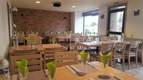 PouldreuzicにあるHotel Restaurant Le Capricorneの木製テーブルと椅子と緑の花瓶のあるレストラン