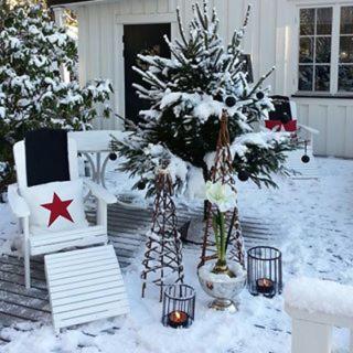 a snow covered patio with a christmas tree and chairs at Det Vita Huset in Stockholm
