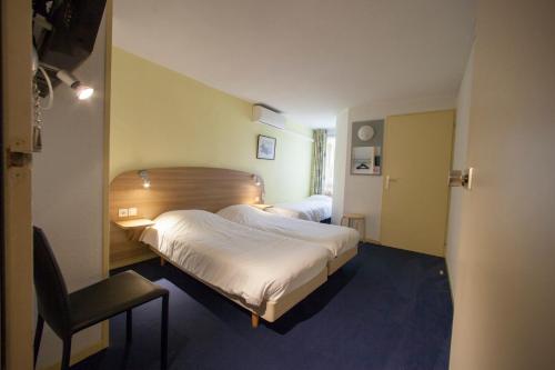 una habitación de hotel con 2 camas y una silla en The Originals City, Hôtel Valence Est en Valence