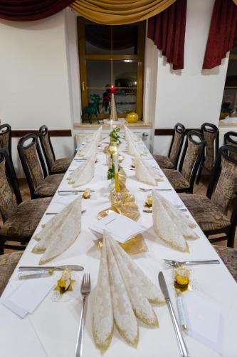 a long table with silverware and napkins on it at Hotel & Ferienwohnungen Bohlenblick in Saalfeld