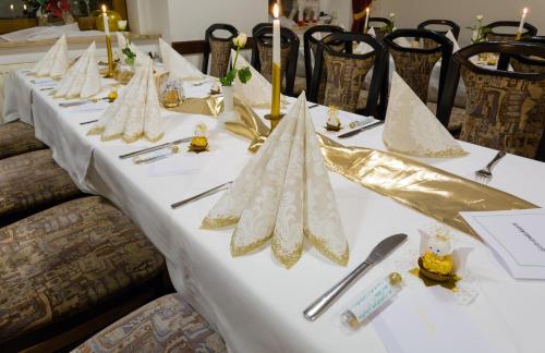 a long table with white table cloth and napkins at Hotel & Ferienwohnungen Bohlenblick in Saalfeld
