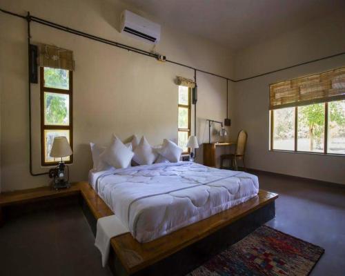 a bedroom with a large bed and two windows at Maati Jungle Lodge Resort Bandhavgarh in Tāla